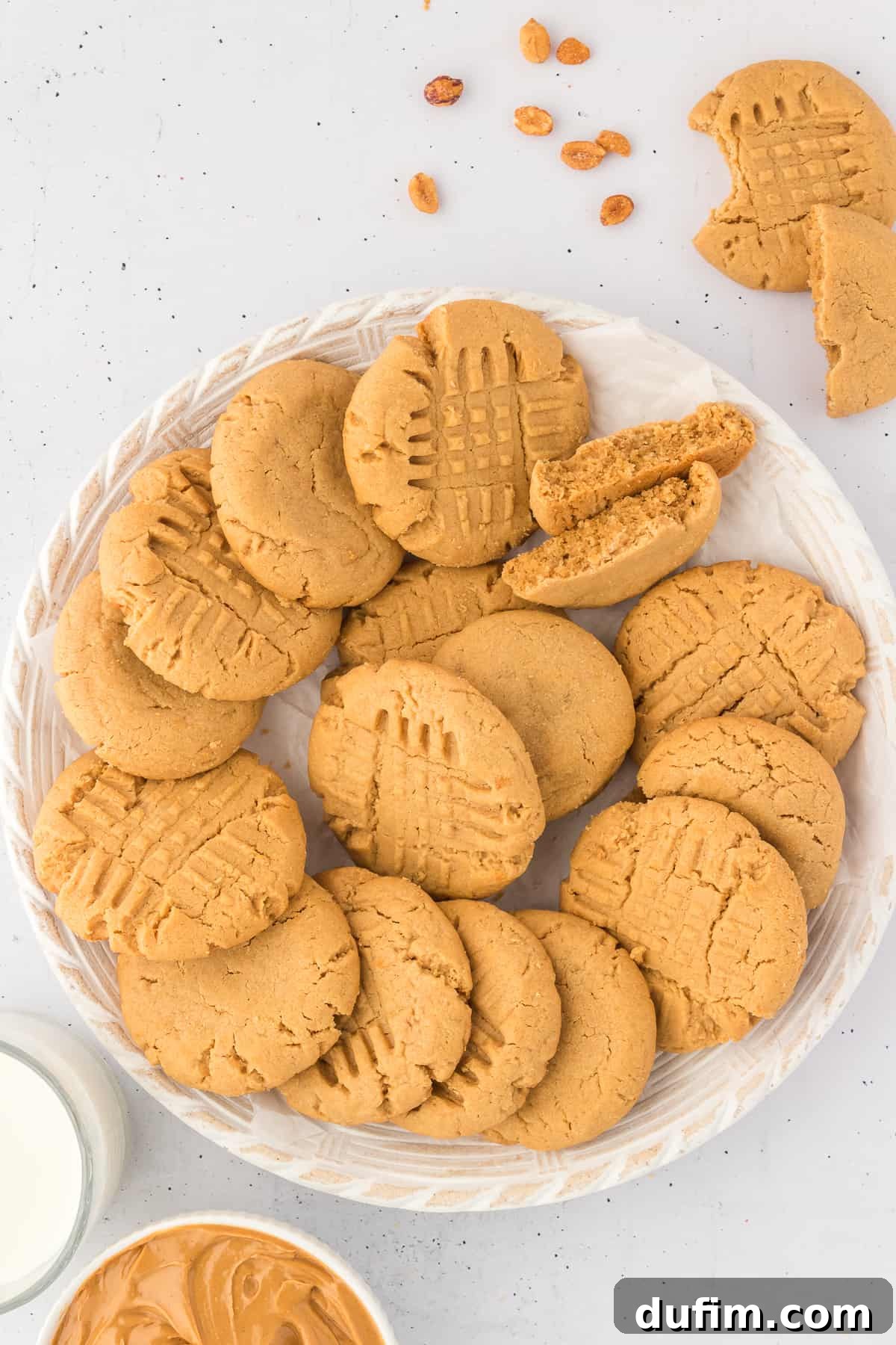 gluten free peanut butter cookies arranged on a white plate with peanuts and more cookies surrounding it