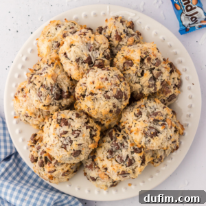 A white plate with a stack of almond joy cookies on it, a blue and white checkered kitchen towel beside is and an almond joy candy bar