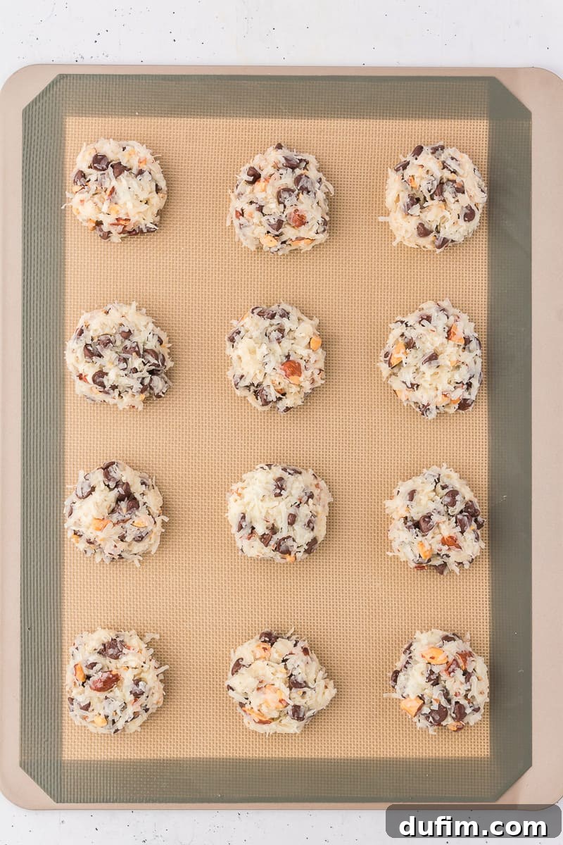 almond joy cookie balls arranged in rows of 3 on a silicone baking mat on a cooking sheet