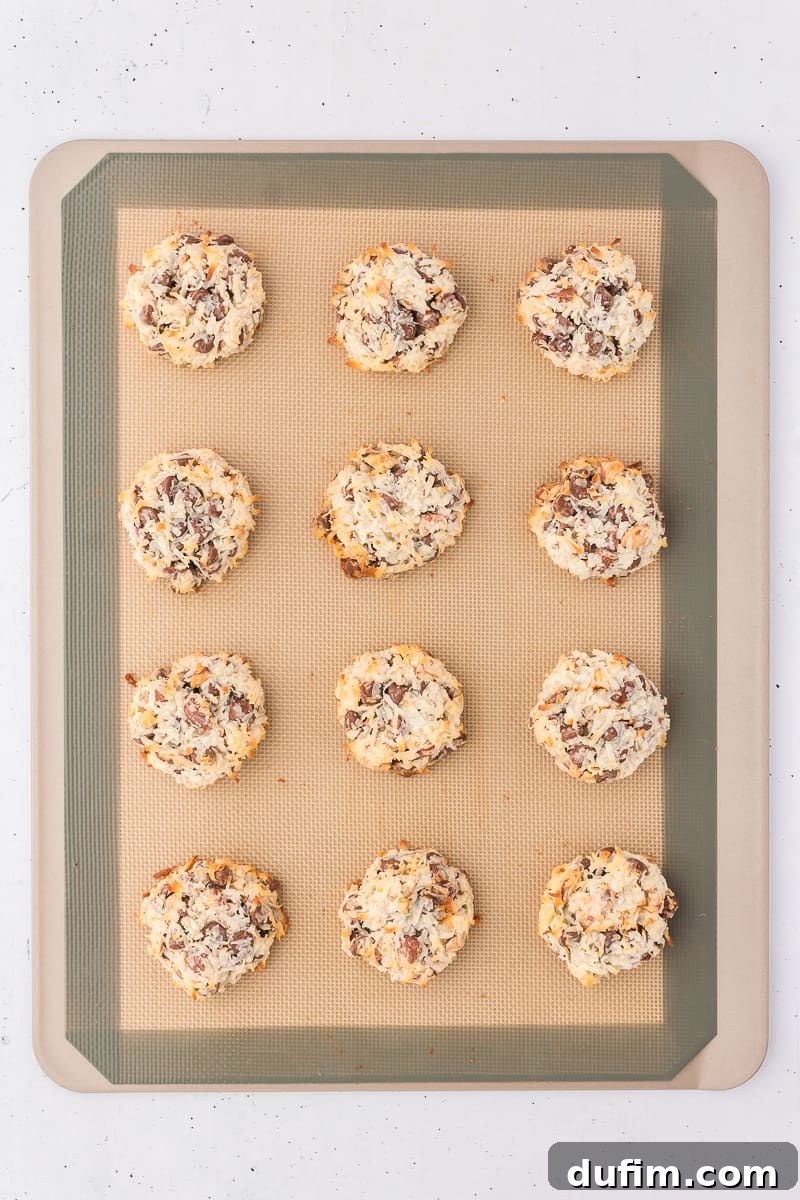 almond joy cookies arranged in rows of 3 on a silicone baking mat on a cooking sheet