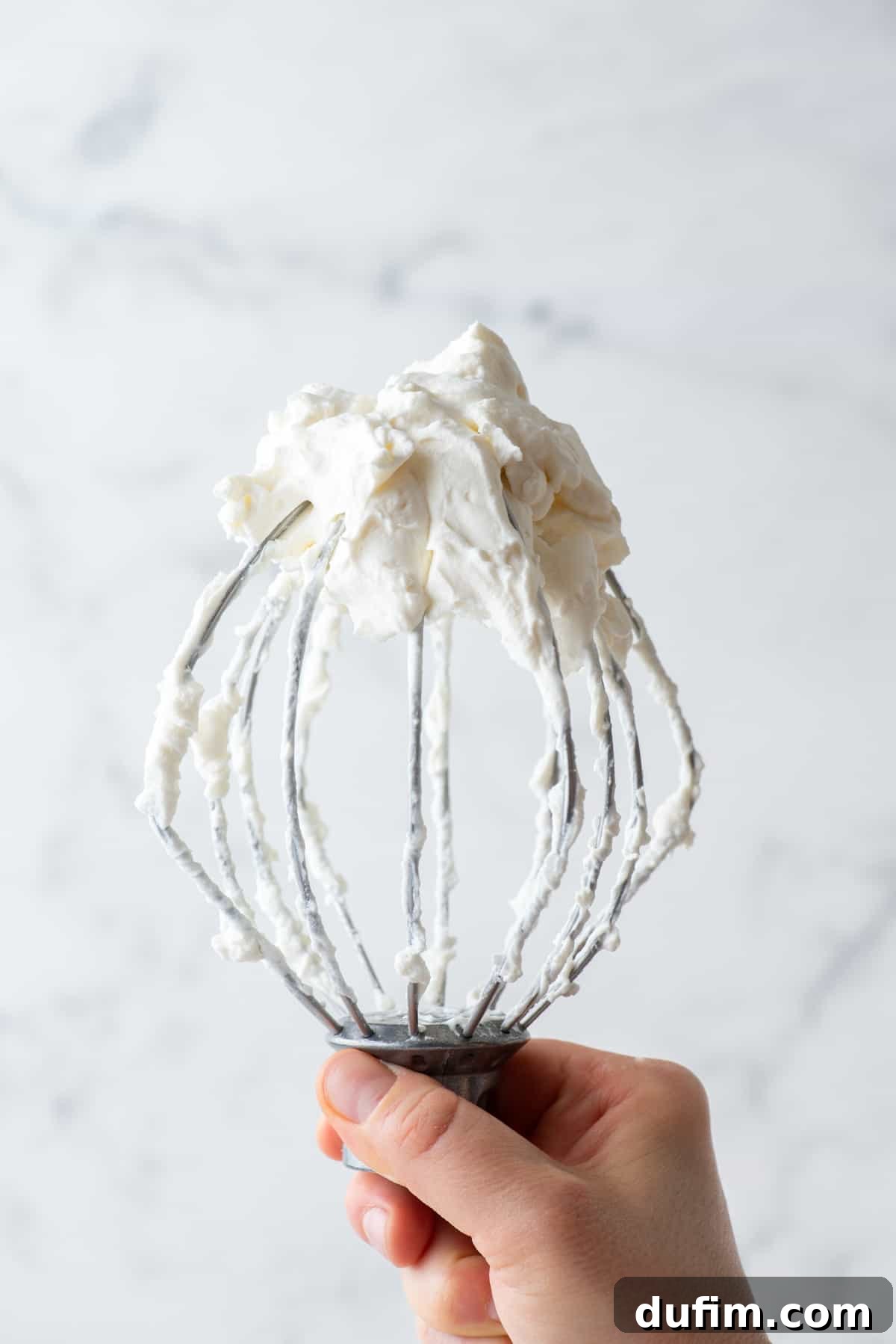 Sweetly Whipped Perfection 4 a hand holding up an electric mixer covered in fresh whipped cream