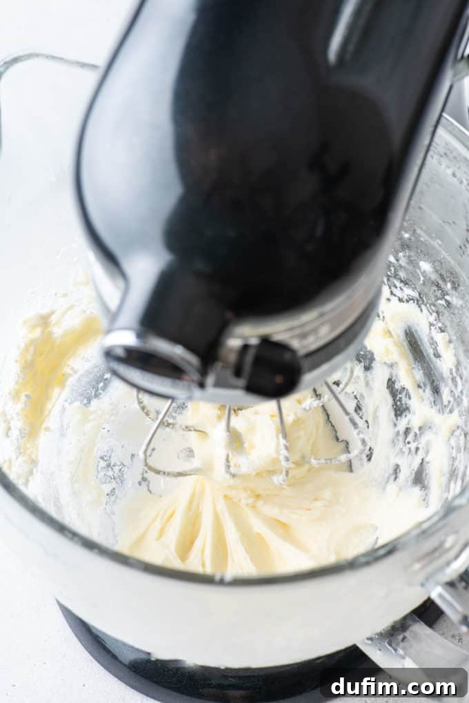 A close-up of the smooth and creamy mixture of cream cheese and powdered sugar in the mixer bowl.