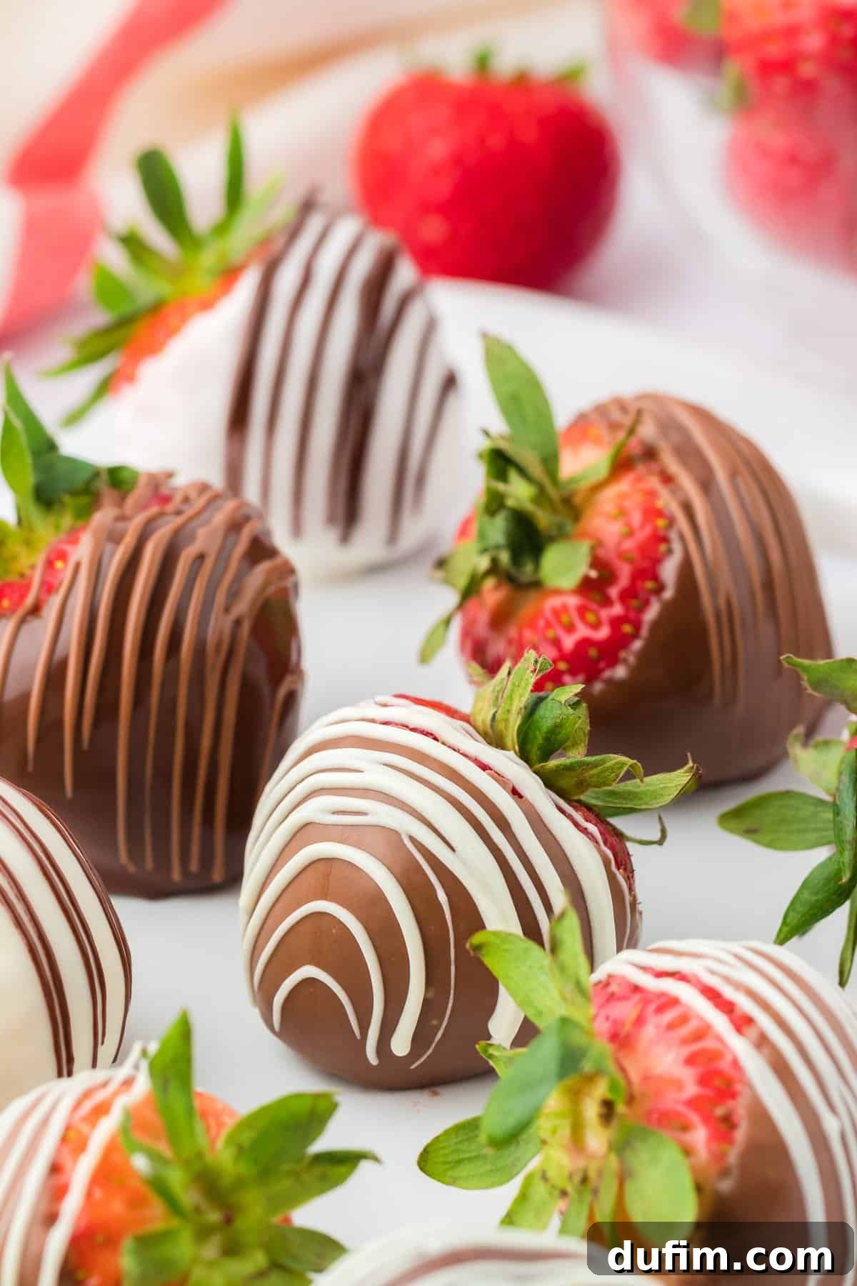 Irresistible Chocolate Dipped Strawberries 2 Close up of a chocolate covered strawberry with a white chocolate drizzle, surrounded by more chocolate strawberries, showcasing a luxurious homemade dessert.