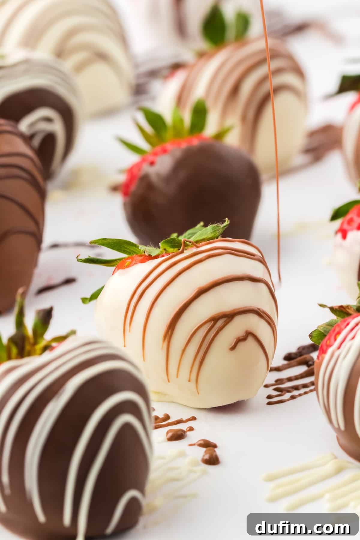 Irresistible Chocolate Dipped Strawberries 11 A white chocolate covered strawberry being artfully drizzled with contrasting milk chocolate, surrounded by other perfectly dipped chocolate strawberries, showcasing decorative possibilities.