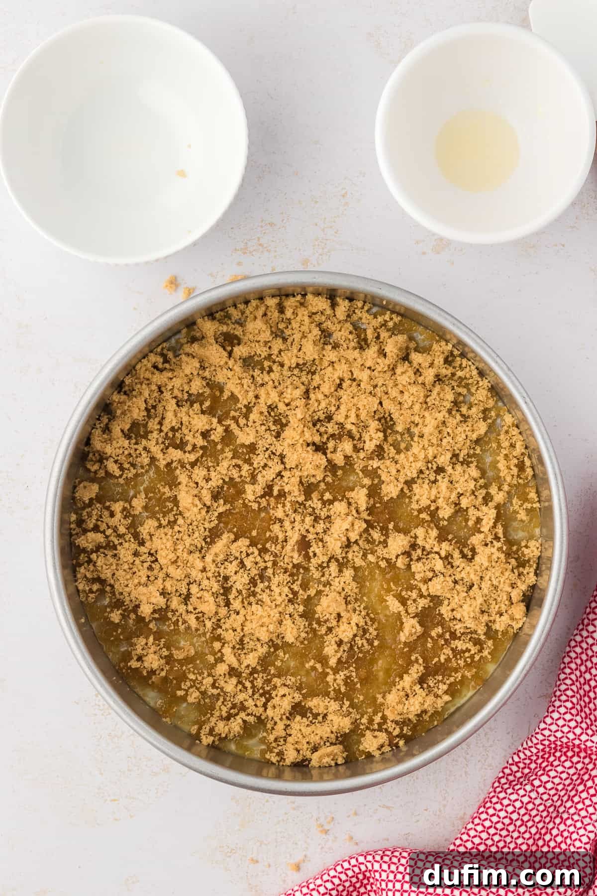 A close-up view of a round cake pan, showing the melted butter and an even layer of brown sugar covering the bottom and sides, creating the base for the upside-down topping.