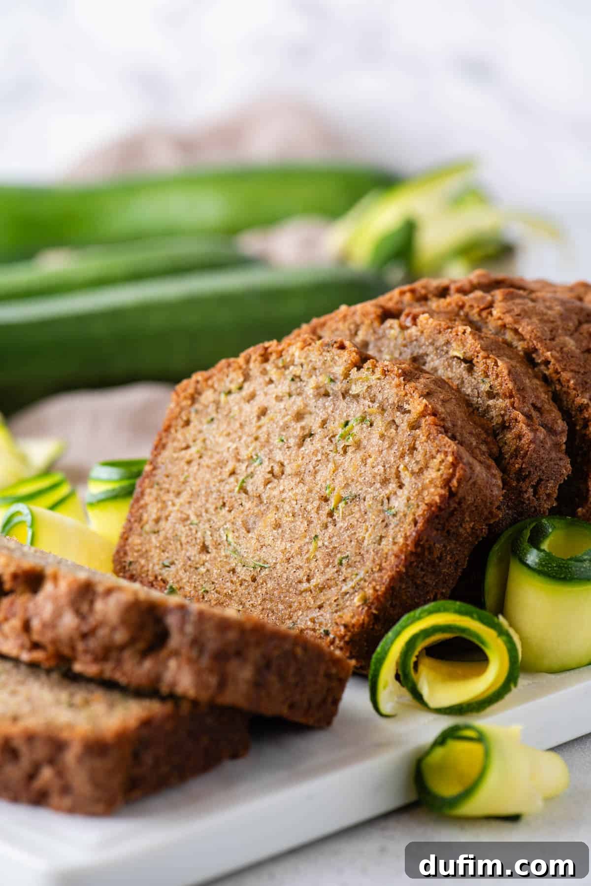 Irresistibly Moist Zucchini Bread 13 Another close-up shot of a deliciously sliced zucchini bread loaf, highlighting its moist and tender interior, with fresh zucchini artfully arranged around it for a rustic touch.