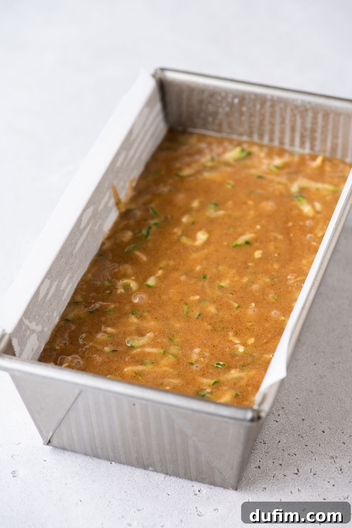 Irresistibly Moist Zucchini Bread 9 Smooth zucchini bread batter perfectly settled into a silver loaf pan, ready for baking.
