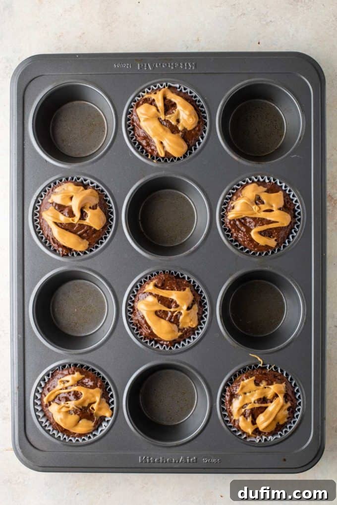 Muffin batter with a completed peanut butter swirl on top, ready for the oven to bake.