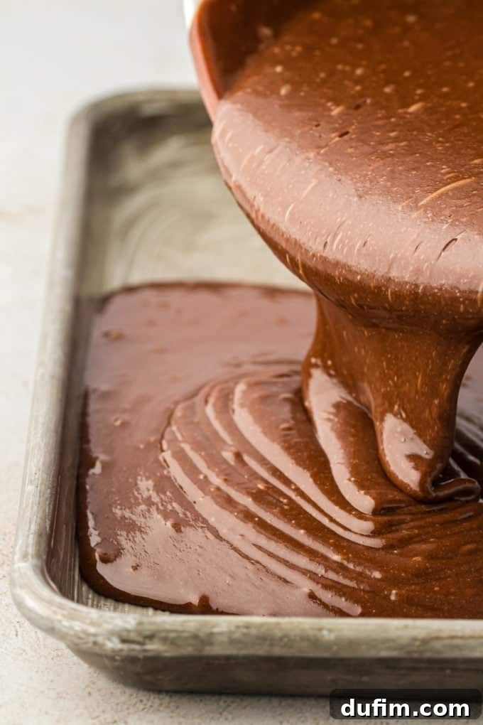 Smooth Texas Sheet Cake batter being carefully poured into the prepared 18x13-inch sheet pan, ready for baking.