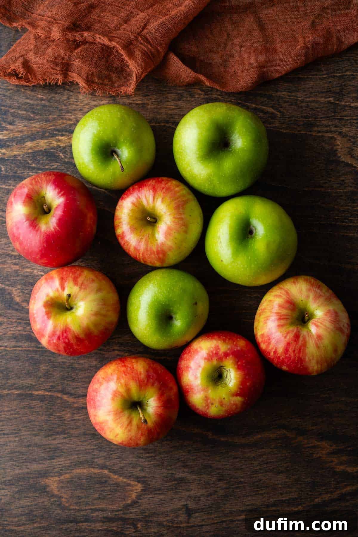 An inviting assortment of different apple varieties, showcasing various shades of red, green, and yellow, arranged beautifully on a rustic wooden surface, highlighting the bounty of apple season.