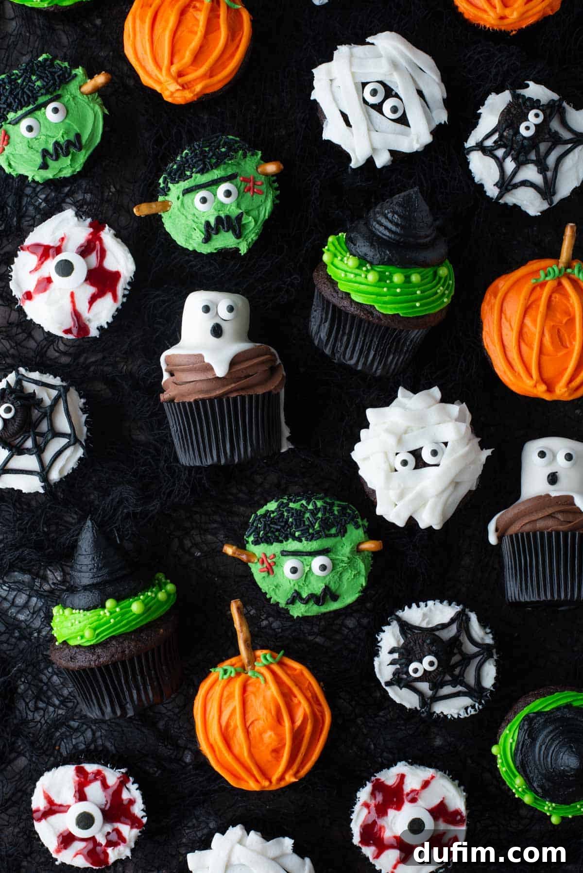 An assortment of festive Halloween cupcakes, including ghost cupcakes, eyeball cupcakes, mummy cupcakes, pumpkin cupcakes, witch hat cupcakes, and spider cupcakes, all creatively decorated.