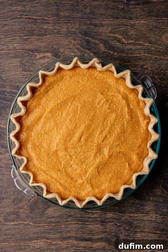 Grandma's Secret Sweet Potato Pie Recipe 12 sweet potato pie ready to be baked in a glass pie dish sitting on a wood surface