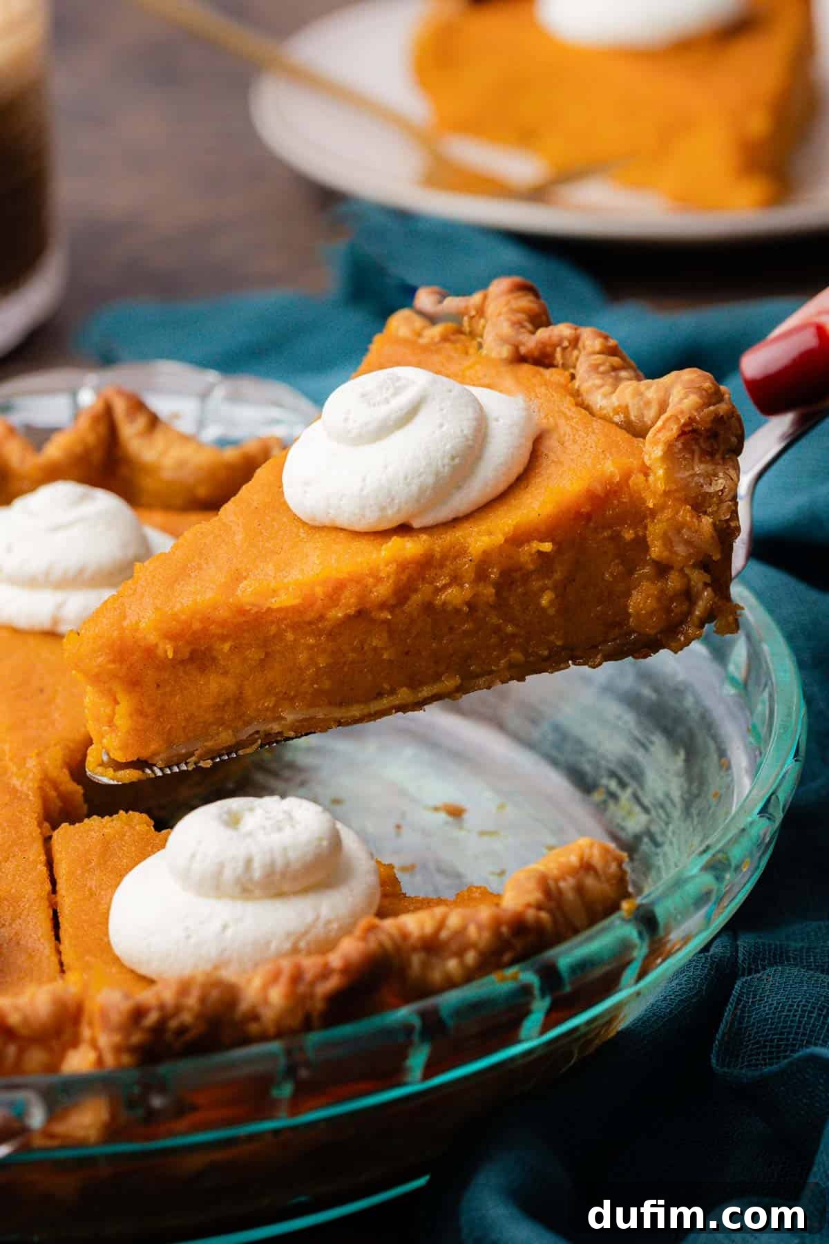 Grandma's Secret Sweet Potato Pie Recipe 14 a slice of sweet potato pie being lifted out of a glass pie dish with more slices of pie in it, all topped with dollops of whipped cream