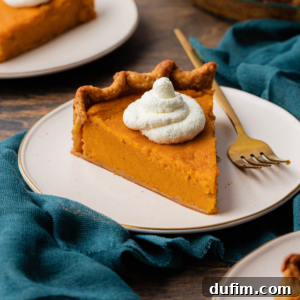 Grandma's Secret Sweet Potato Pie Recipe 16 slices of sweet potato pie topped with dollops of whipped cream on small white places on a dark teal towel on a wood surface with a fork laying beside the pie on the middle plate