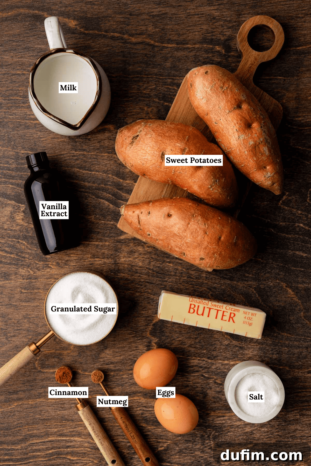 Grandma's Secret Sweet Potato Pie Recipe 4 ingredients for sweet potato pie arranged on a wood surface including whole sweet potatoes, milk, vanilla extract, granulated sugar, butter, eggs, salt, nutmeg and cinnamon