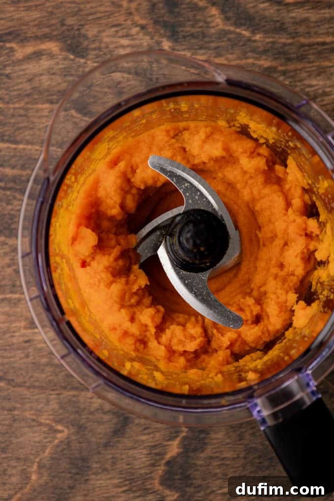 Grandma's Secret Sweet Potato Pie Recipe 8 sweet potato that has been mashed in a food processor bowl sitting on a wood surface