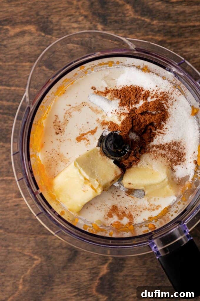 Grandma's Secret Sweet Potato Pie Recipe 9 mashed sweet potato, milk, sugar, cinnamon, nutmeg and butter in a food processor bowl sitting on a wood surface