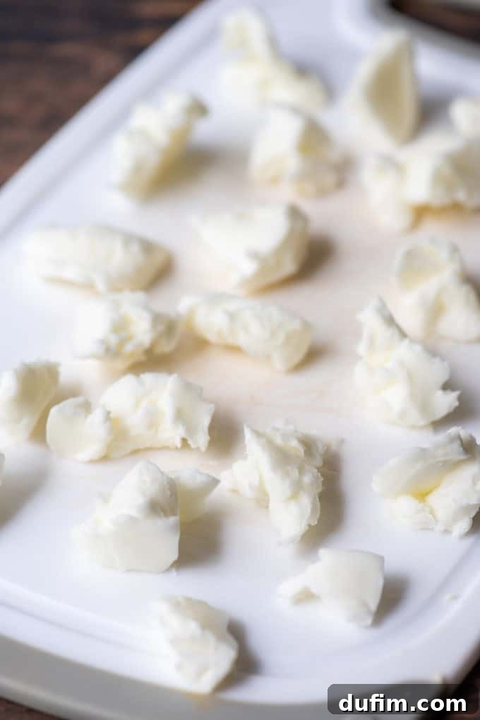 Small, distinct chunks of chilled vegetable shortening spread on a white cutting board, ready for incorporation into the dry ingredients.