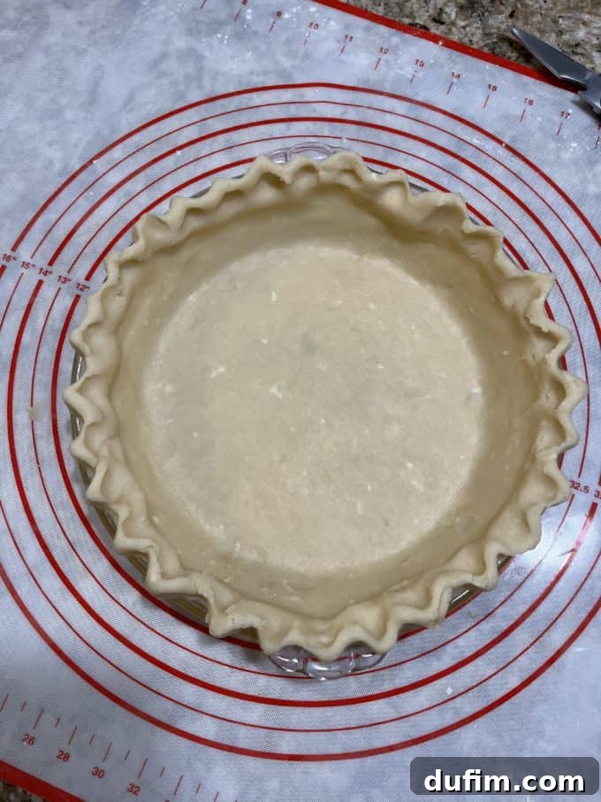 A beautifully fluted gluten-free pie crust in a glass pie dish, resting on a pie mat, indicating a successful outcome.