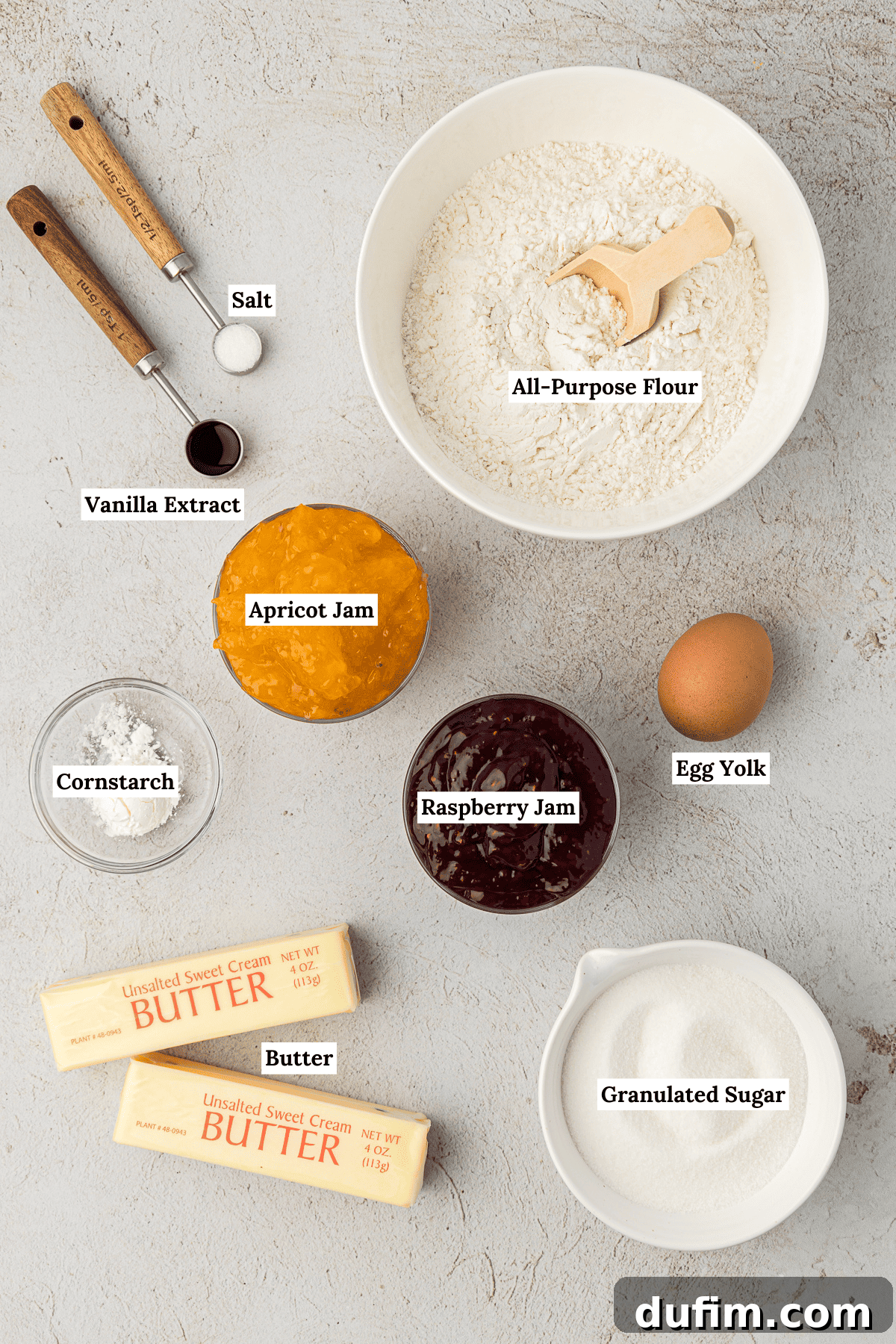 THUMBPRINT COOKIES: A TIMELESS DELIGHT 4 Ingredients for classic thumbprint cookies laid out: all-purpose flour, vanilla extract, salt, an egg yolk, cornstarch, softened butter, jars of vibrant raspberry and apricot jam, and granulated sugar, ready for baking.