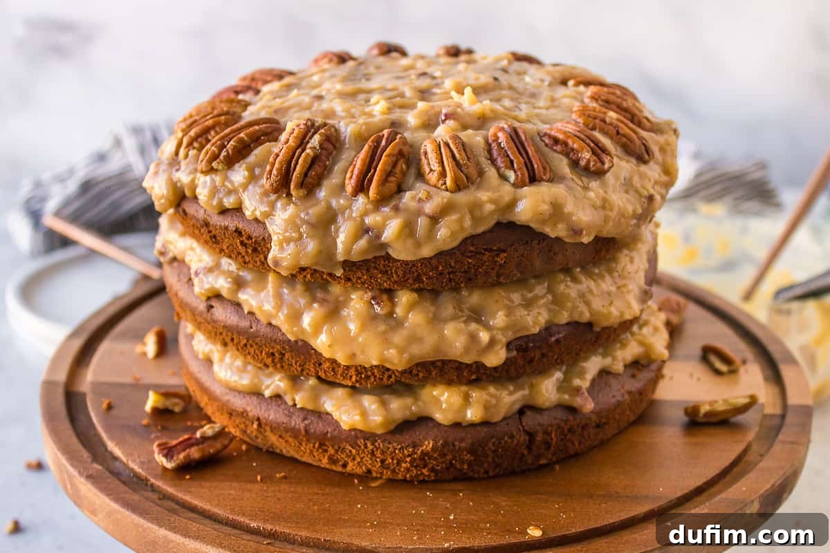 German chocolate cake on a wood serving platter with pecans sprinkled around it, ready to be served.