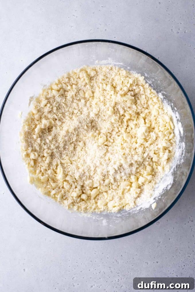 Ingredients for butter cookies partially mixed together in a clear glass bowl, showcasing the initial stages of butter and sugar creaming.