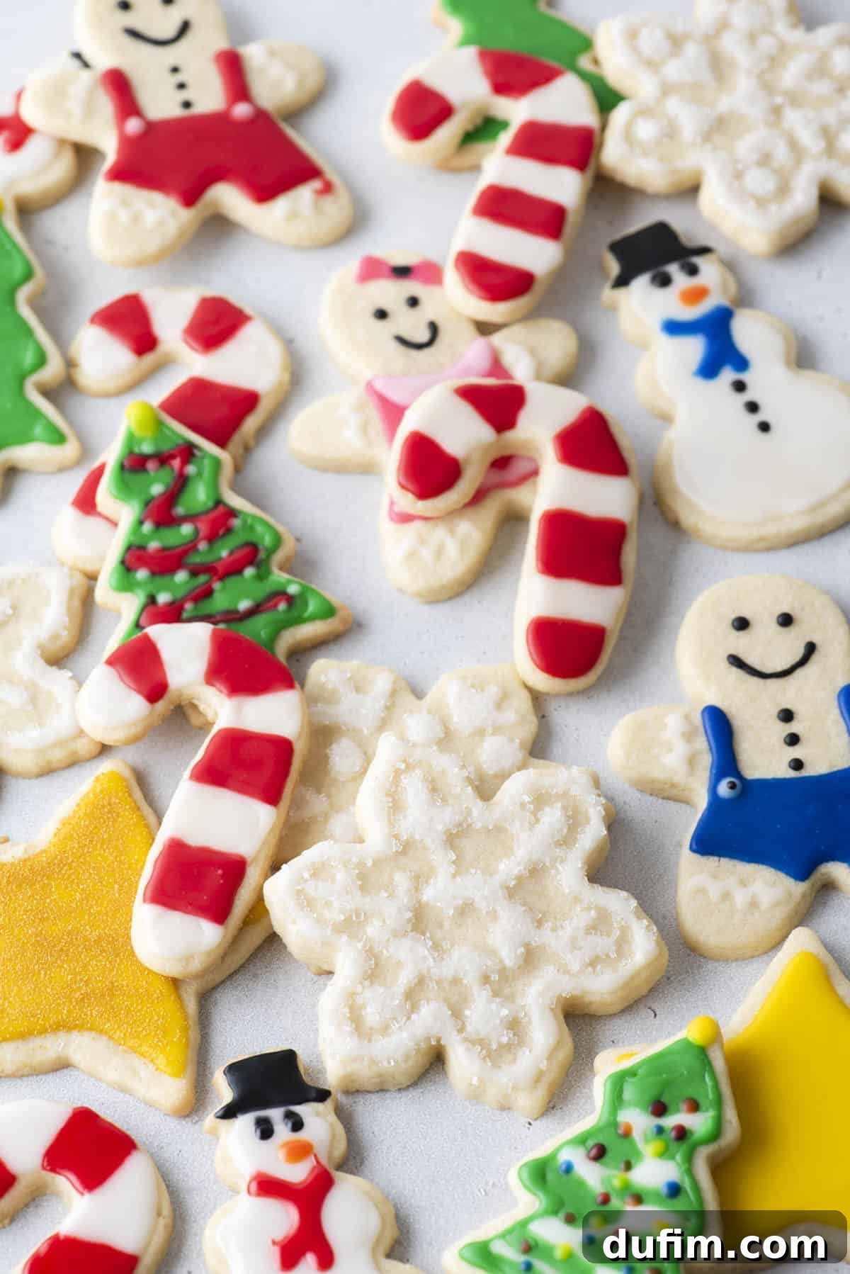 An assortment of festive Christmas cookies decorated with royal icing, including candy canes, Christmas trees, snowmen, and snowflakes, arranged artfully.