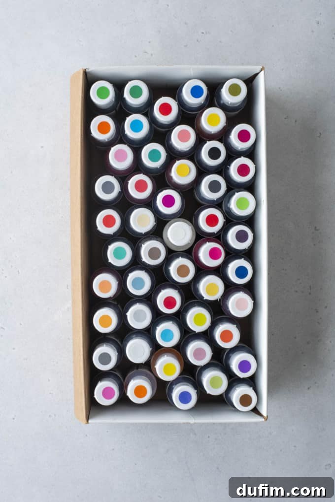 Overhead view of a box full of gel food coloring bottles with colored dots on top, indicating the color of each.