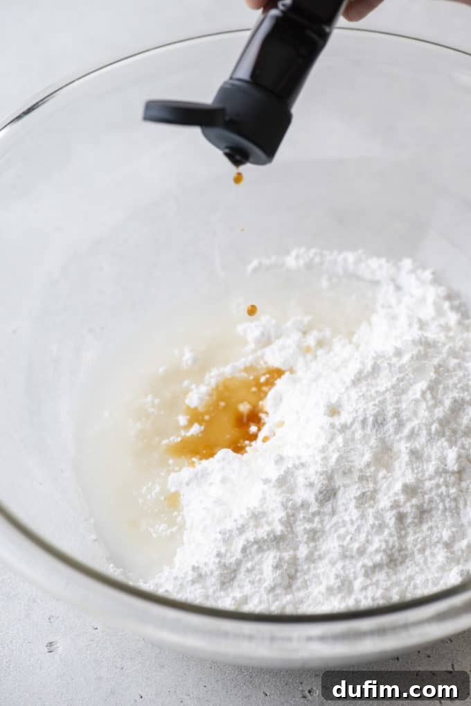 All ingredients for royal icing in a clear glass bowl.