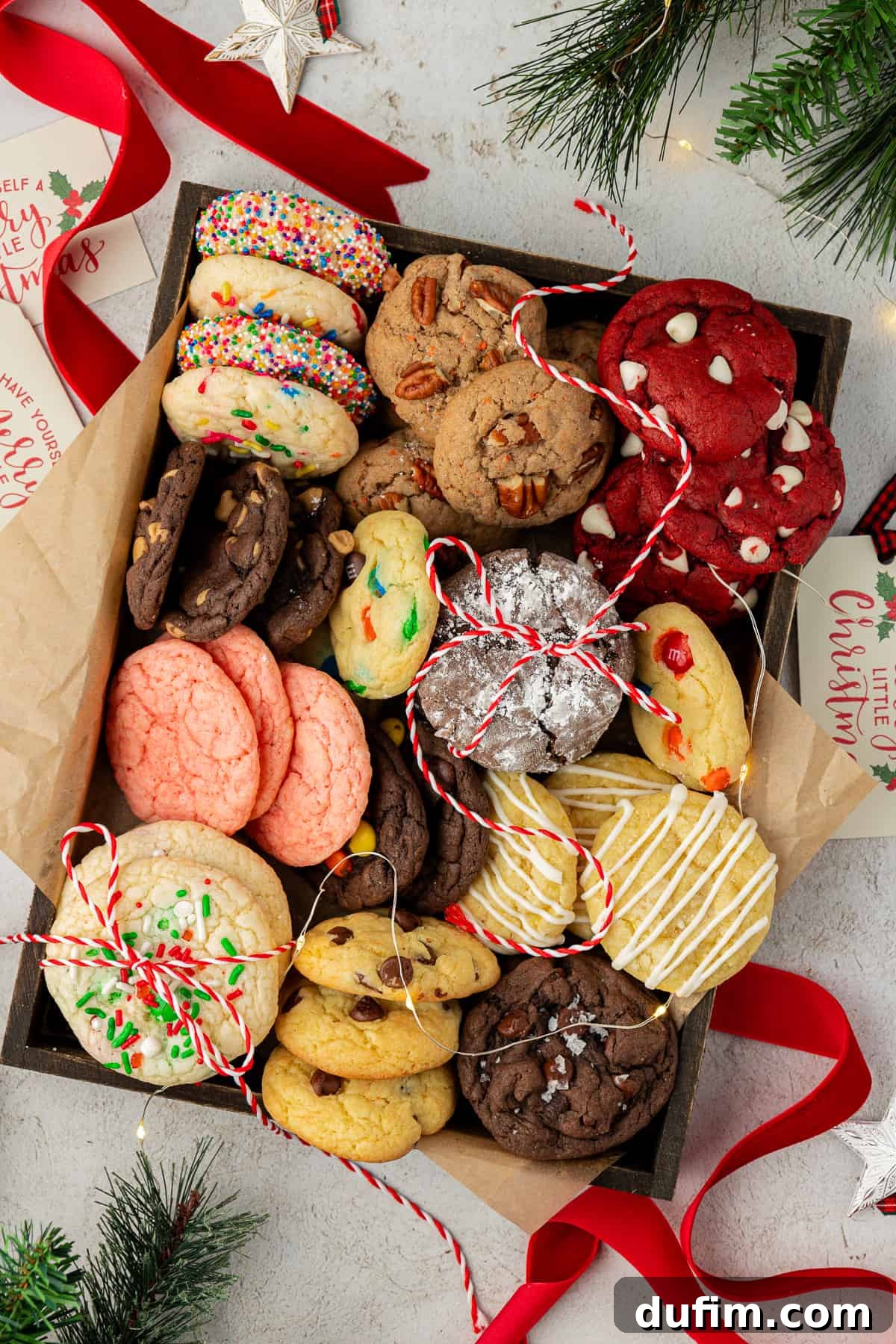 A beautifully arranged box filled with an assortment of soft and chewy cake mix cookies, tied with a festive red ribbon. Pine stems and red and white string add a charming touch, perfect for gifting.