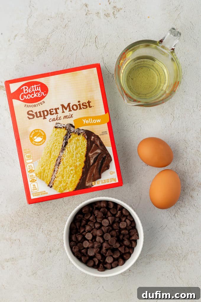 Ingredients for classic chocolate chip cake mix cookies: a box of yellow cake mix, a generous amount of chocolate chips, two fresh eggs, and vegetable oil, neatly laid out and ready for baking.