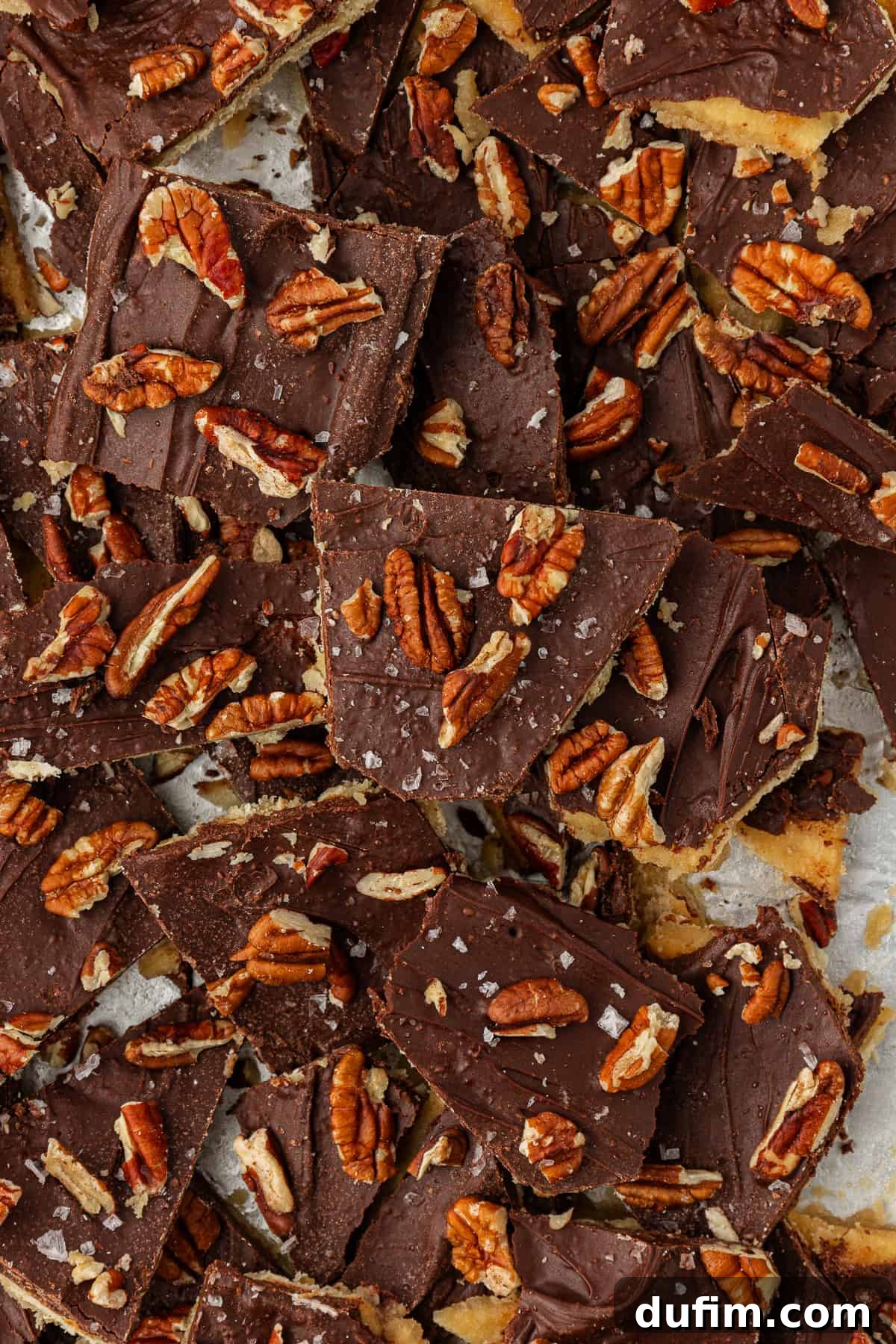 Close-up photo of a delicious pile of Christmas Crack candy, perfectly topped with crunchy pecans and a light dusting of sea salt.