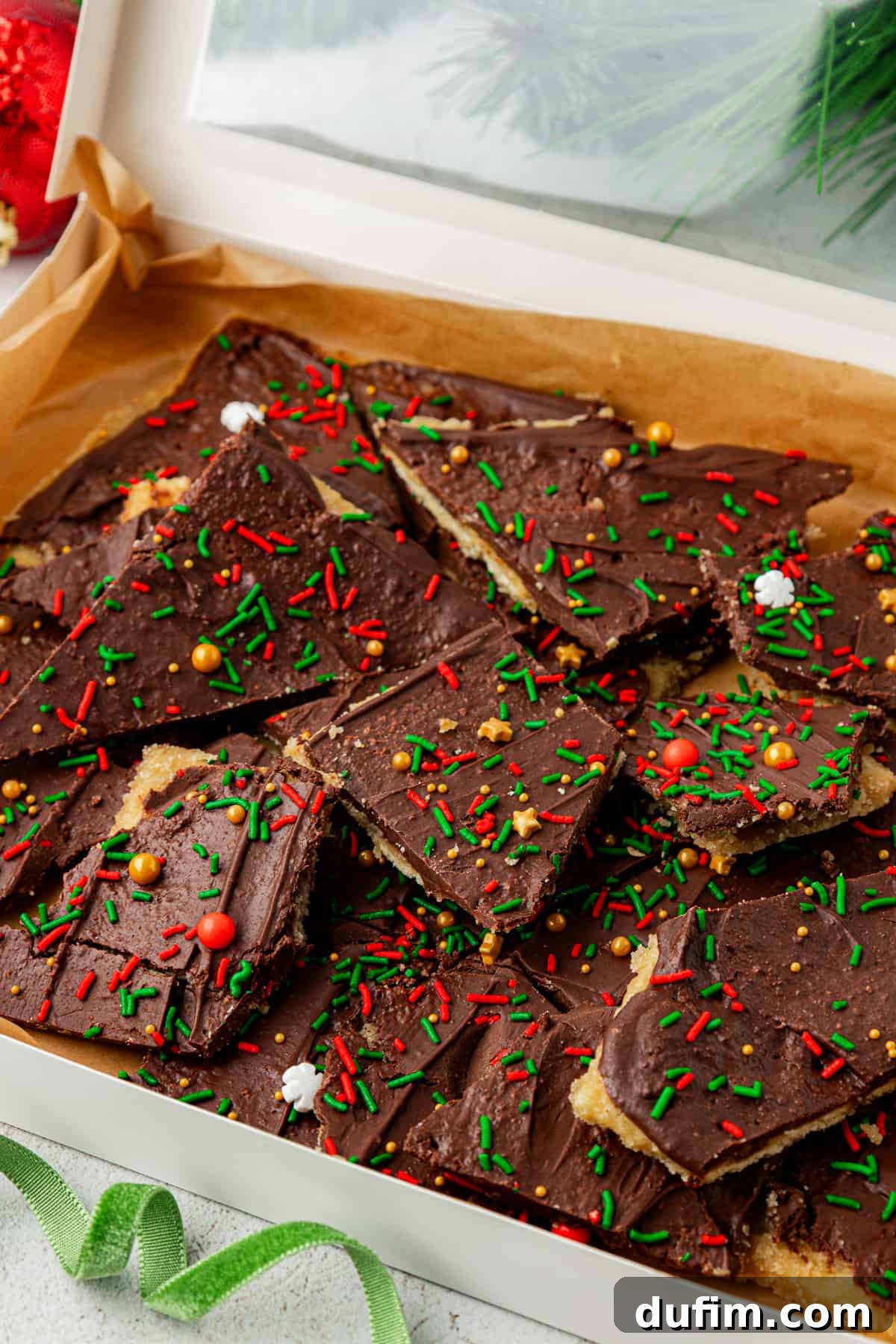 A festive box of Christmas Crack candy adorned with a green ribbon, ready for gifting.