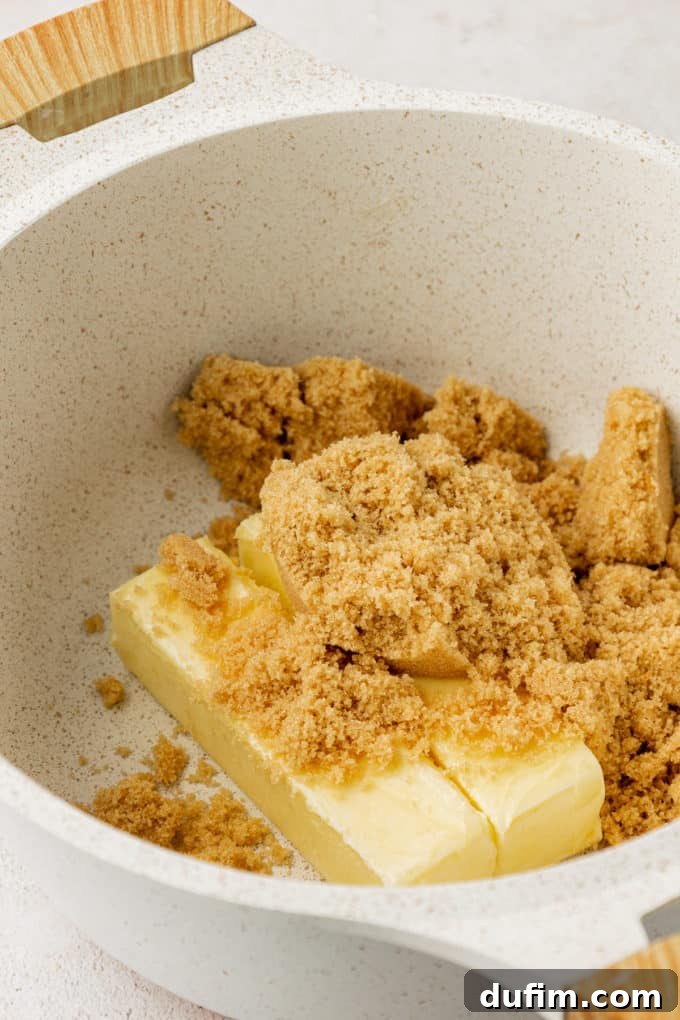 Brown sugar and two sticks of unsalted butter melting in a white saucepan over medium heat.