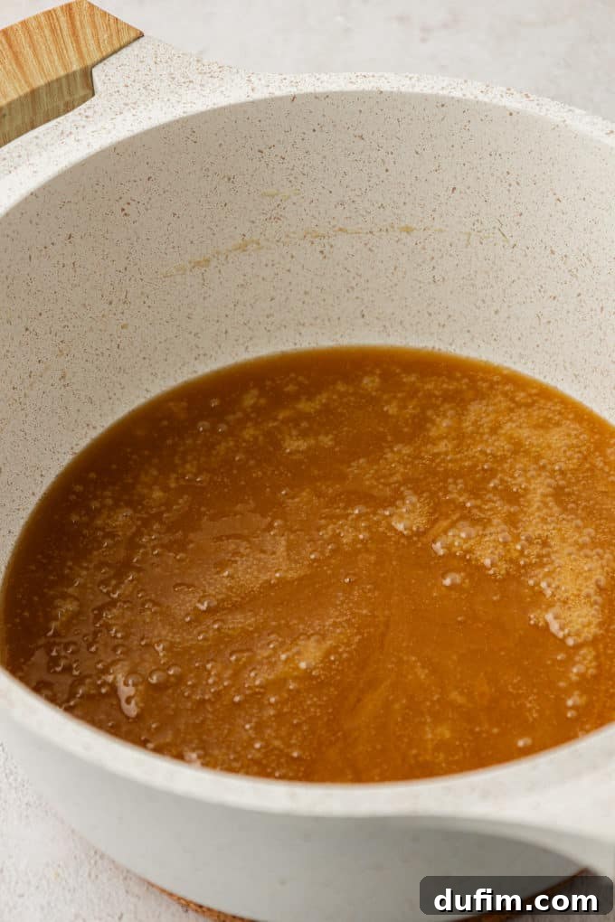 A smooth, melted brown sugar and butter mixture bubbling in a white saucepan, achieving a rich caramel color.