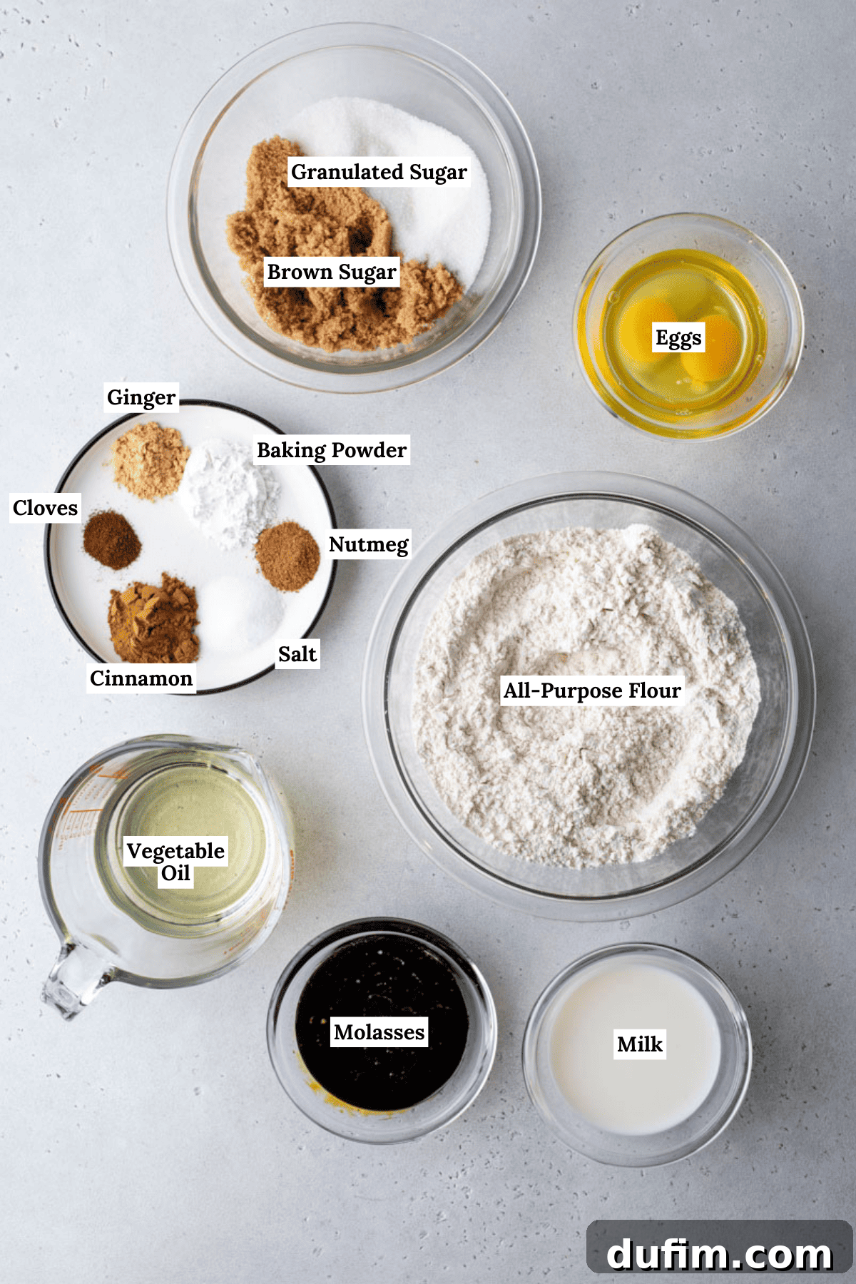 A collection of gingerbread muffin ingredients neatly arranged in bowls on a pristine white background, ready for baking.