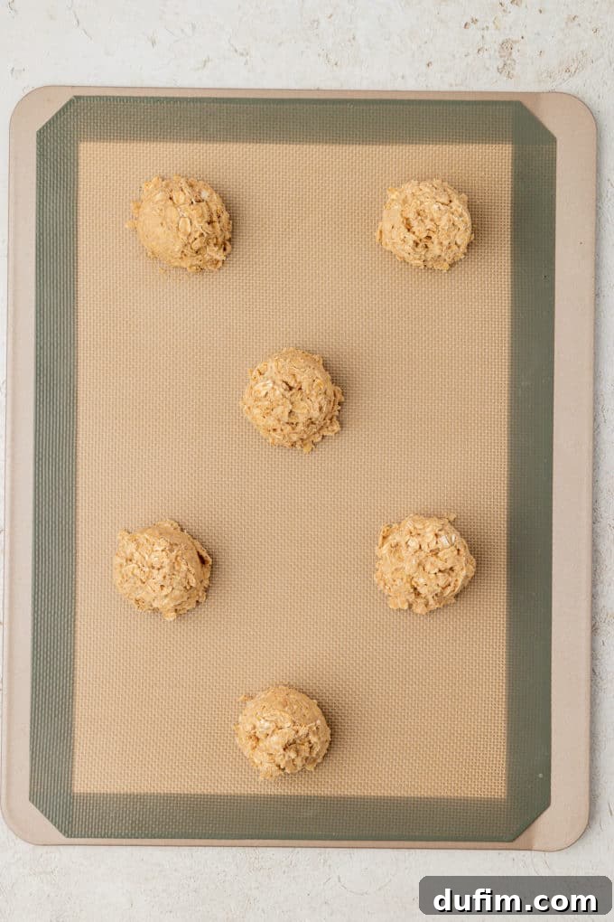 oatmeal cookie dough balls on a silicone baking mat on a baking sheet
