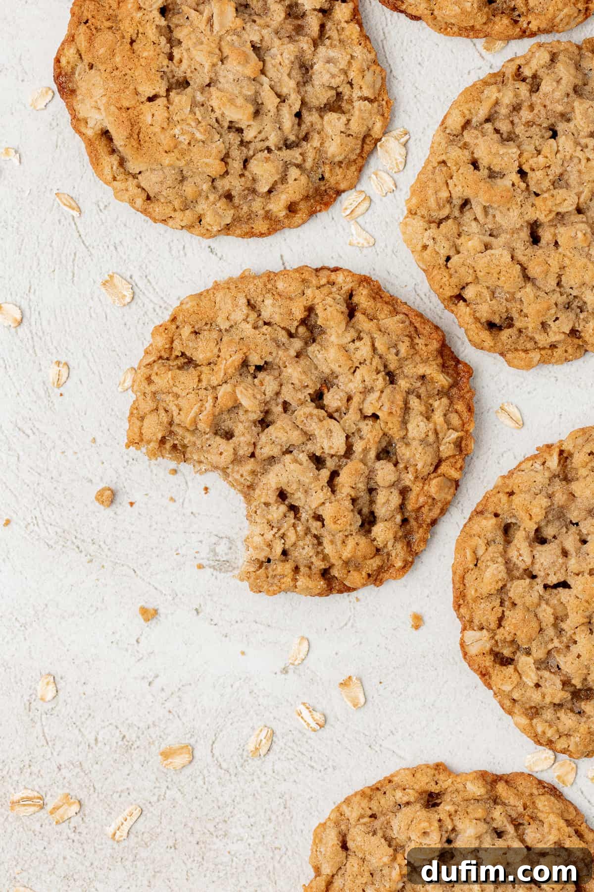 overhead view of oatmeal cookies laying flat with a bite out of one of the cookies and oats sprinkled around