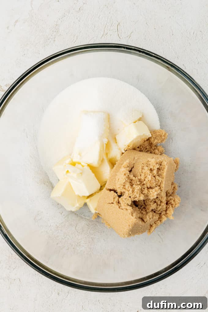 a clear glass bowl containing butter, granulated sugar and brown sugar