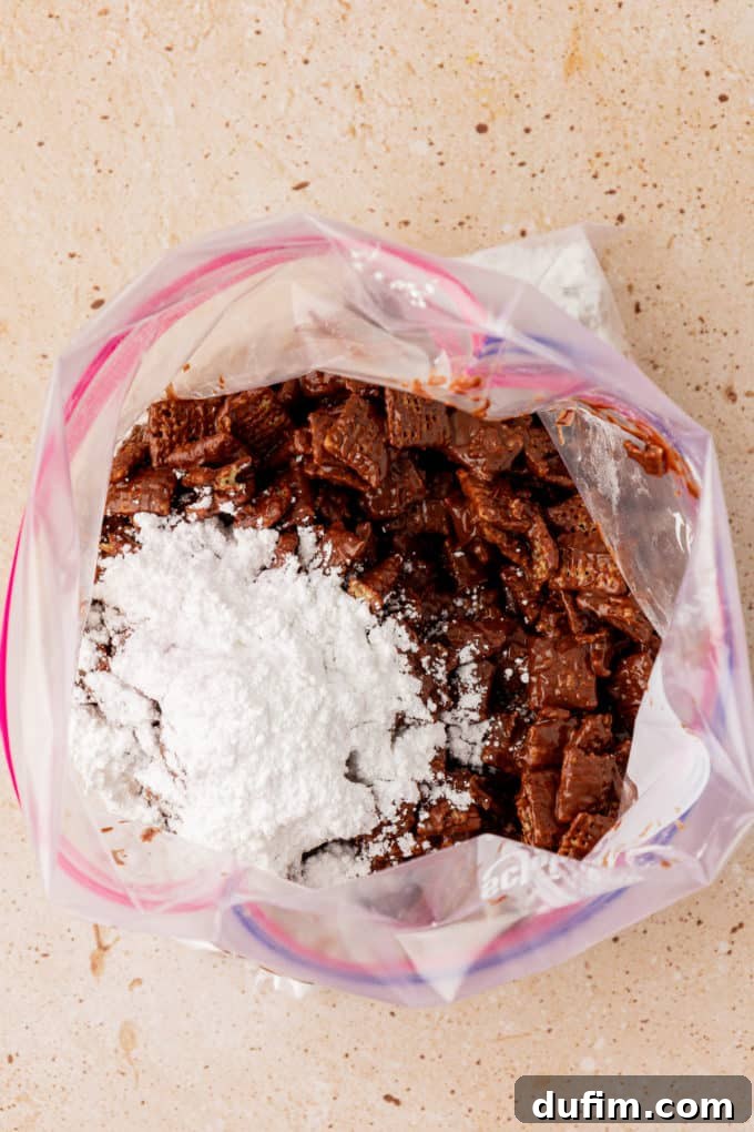 chex cereal coated in chocolate in a large ziploc bag with a pile of powdered sugar on top