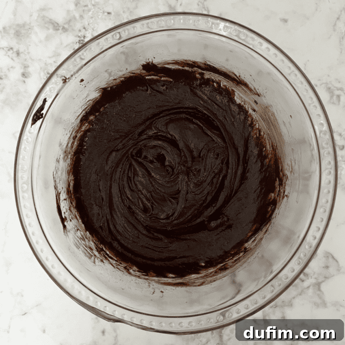 Decadent Flourless Chocolate Cake 13 Eggs being stirred into the chocolate mixture, which is now thick