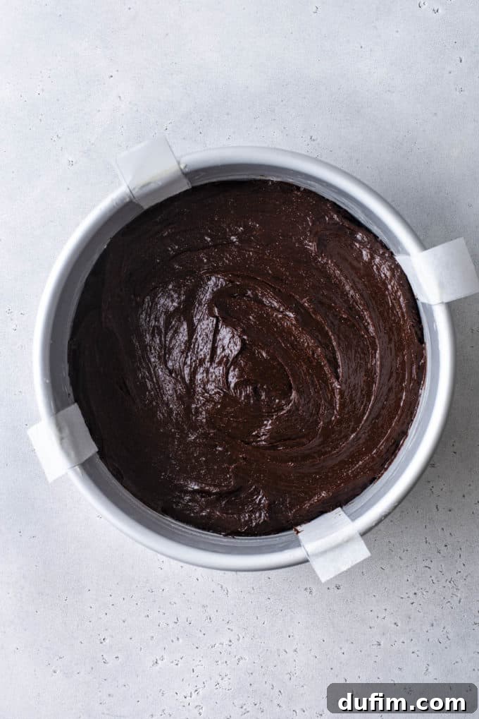 Decadent Flourless Chocolate Cake 14 flourless chocolate cake batter in a round cake pan with four parchment paper handles sticking out the sides