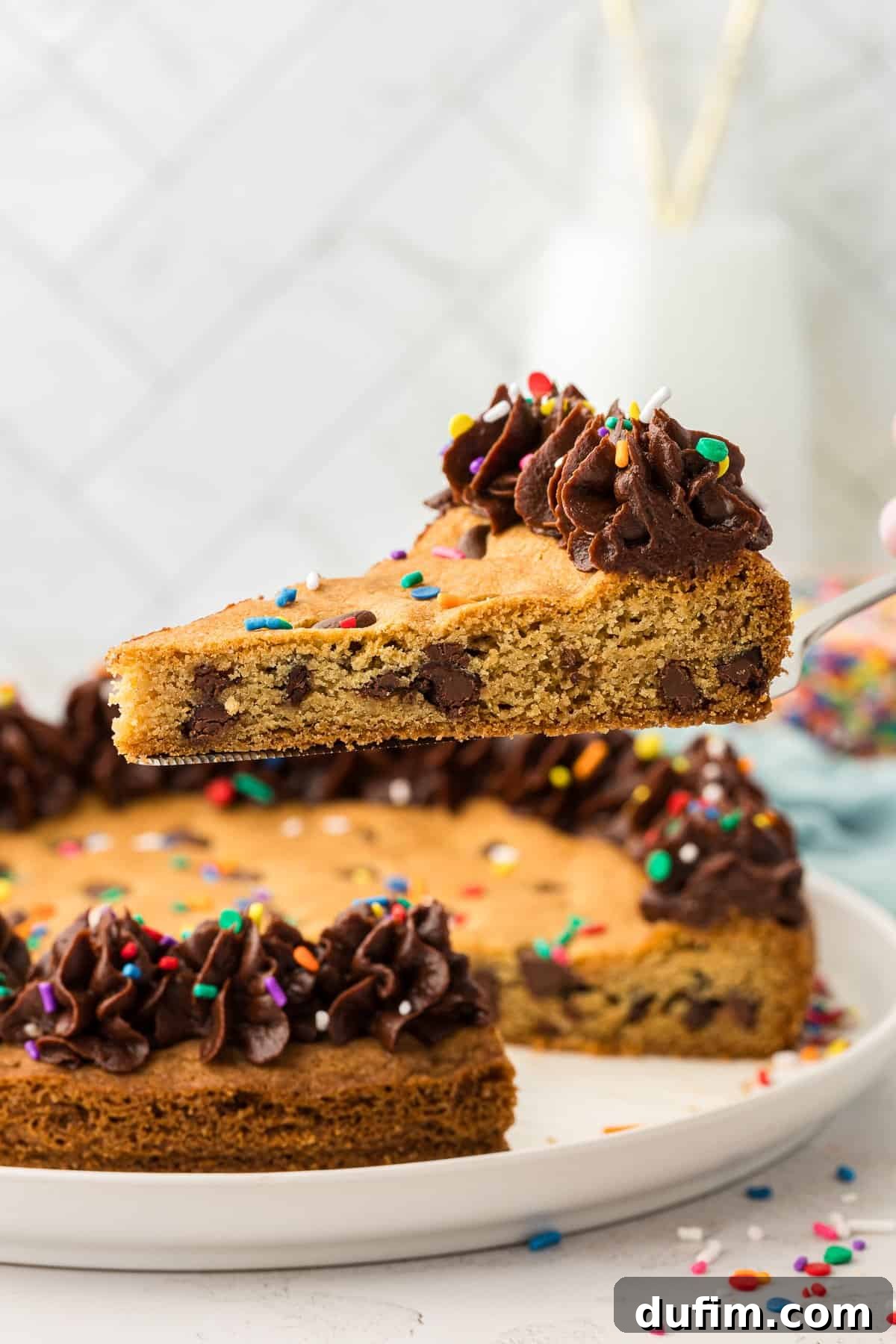 A perfectly baked slice of homemade chocolate chip cookie cake being lifted by a spatula, showcasing its soft, chewy texture and rich chocolate chips.