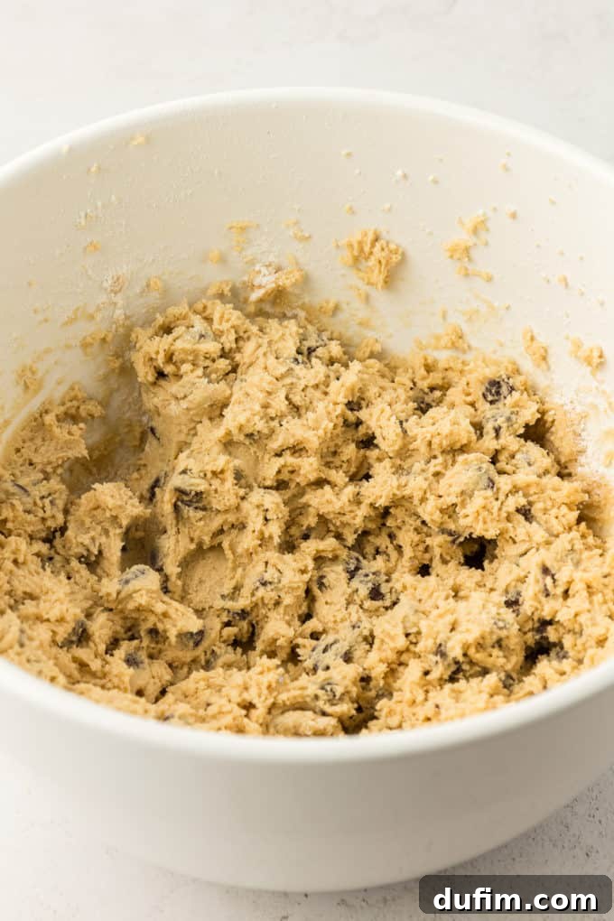 The thick, perfectly mixed cookie cake batter in a white bowl, ready to be transferred to the baking pan.