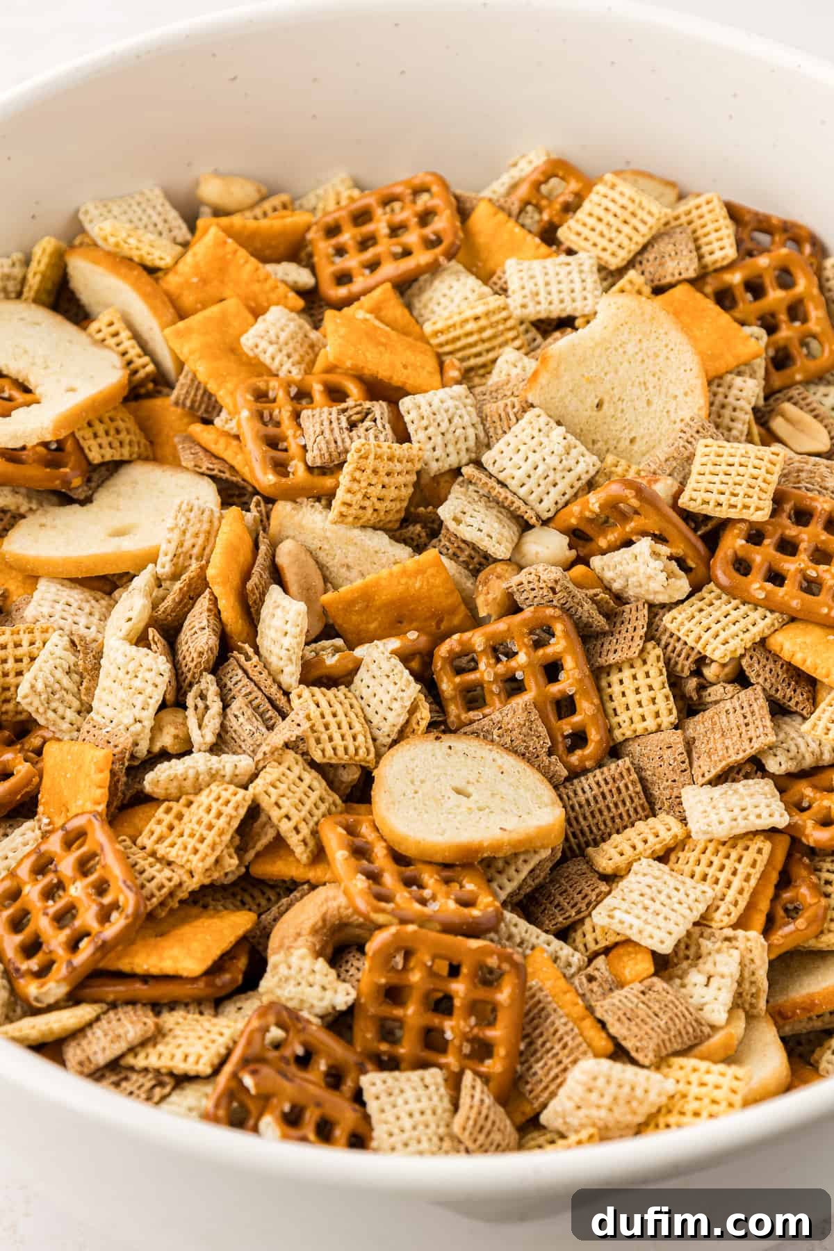 Unlock the Secret to Perfect Chex Mix 14 A crisp, clean white bowl filled to the brim with perfectly golden, homemade Chex Mix, highlighting its delicious texture and readiness to be served.