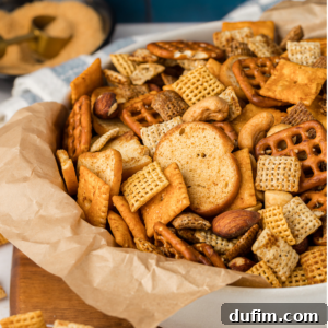 A white bowl lined with brown paper, filled with homemade Chex Mix, a perfectly seasoned snack for any occasion.