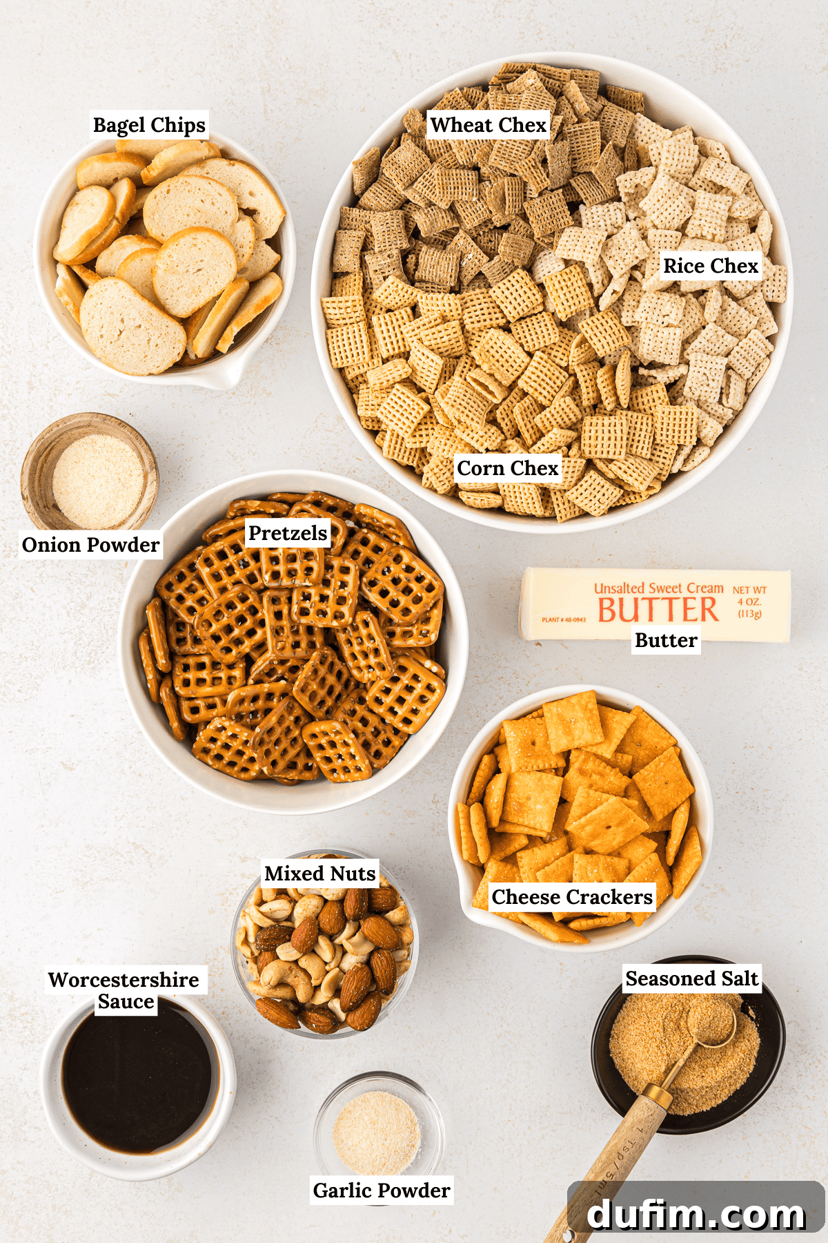 Unlock the Secret to Perfect Chex Mix 3 Overhead view of all the ingredients laid out for homemade Chex Mix, including Corn, Rice, and Wheat Chex cereals, mixed nuts, mini pretzels, cheese crackers, mini bagel chips, a stick of butter, Worcestershire sauce, seasoned salt, garlic powder, and onion powder.
