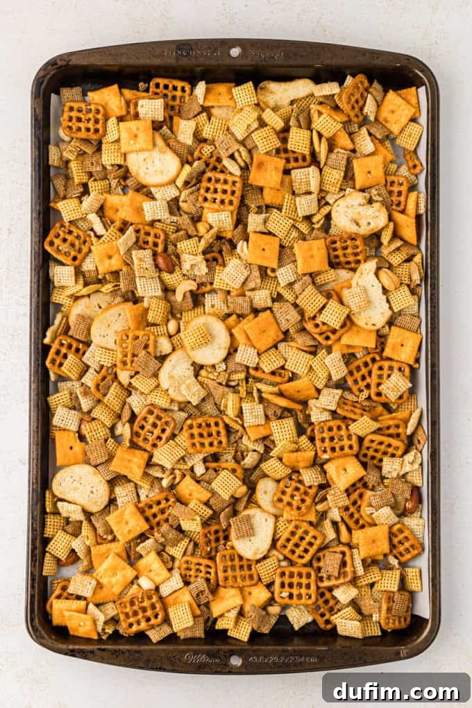 Unlock the Secret to Perfect Chex Mix 9 A baking sheet filled with evenly spread homemade Chex Mix before baking, showing the individual components well-coated.