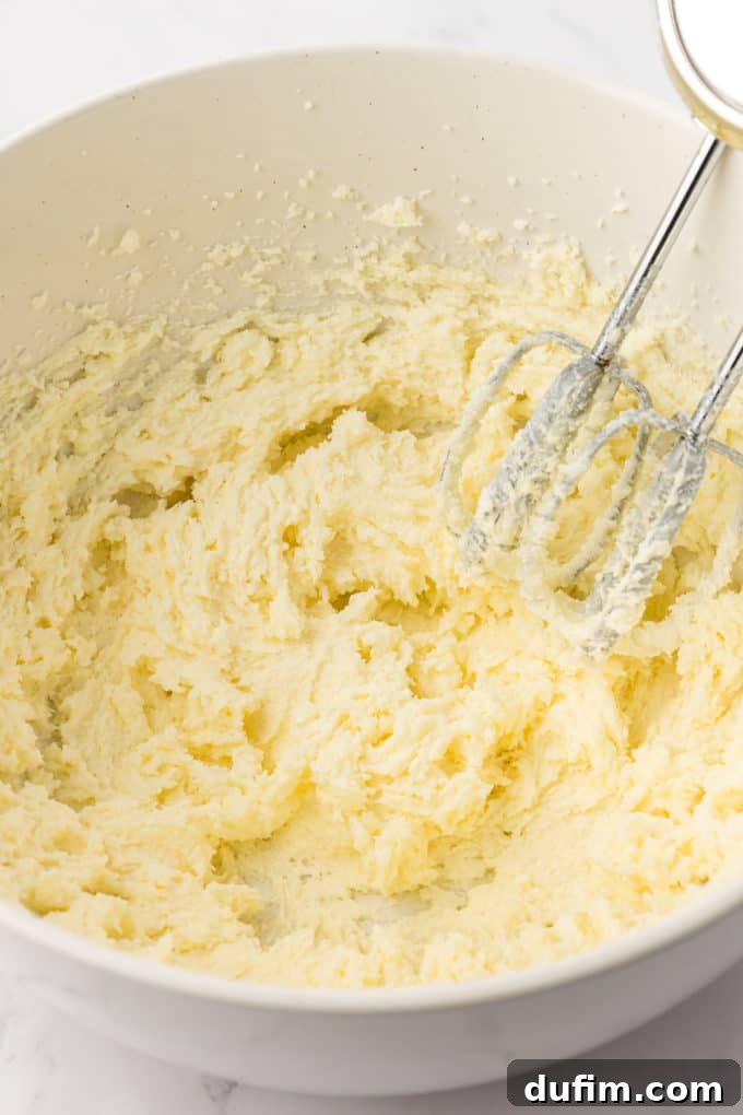 wet ingredients for vanilla bundt cake in a white bowl with the whisks of an electric mixer leaning inside the bowl