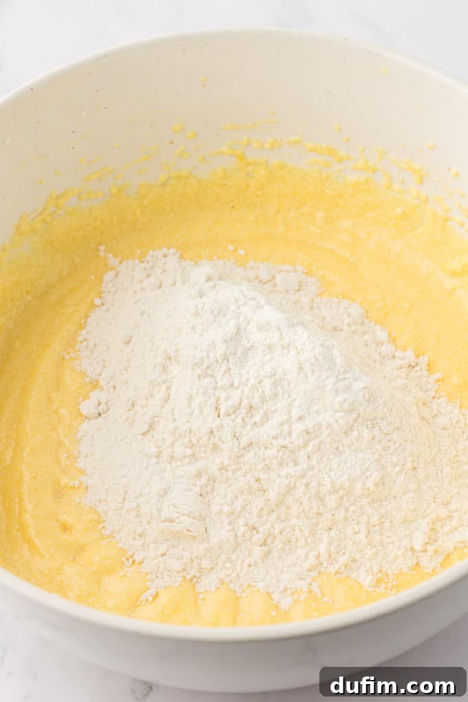 wet ingredients for bundt cake in a white bowl with dry ingredients on top that haven't been mixed in yet